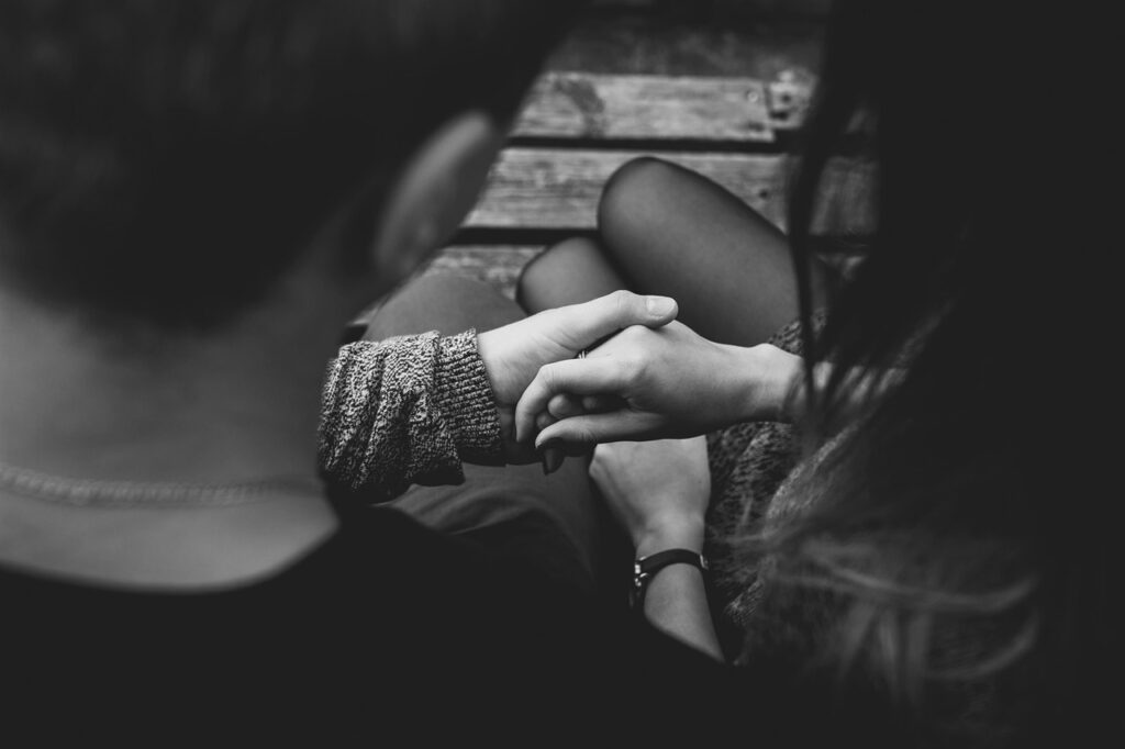 Black-and-white close-up of a couple holding hands, symbolizing love, connection, and support through life's journe